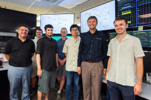 A group of 7 people in front of monitors