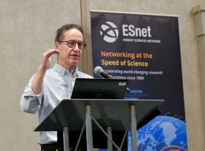 Mark Foster (SLAC) Photo of person standing at podium speaking, with ESnet sign behind them.