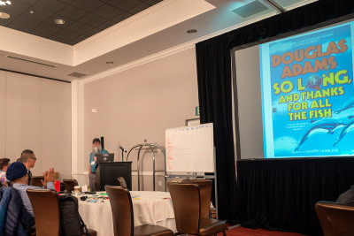 Man at podium with book cover on screen
