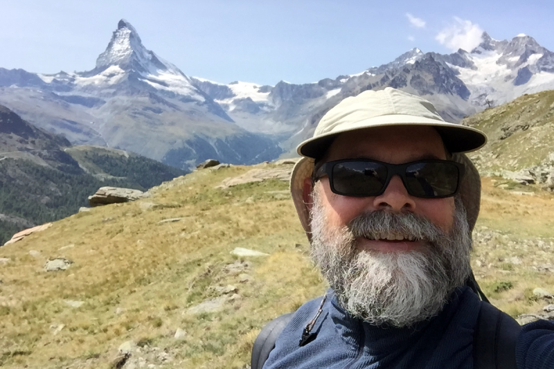 Man in hat in front of mountains