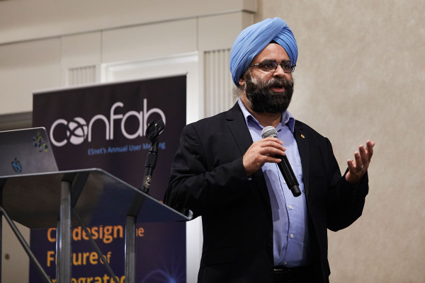 Inder Monga standing at a podium with a mic in his hand