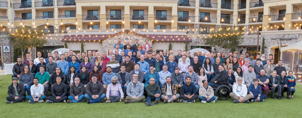 Large group of people assembled outside on tables and grass