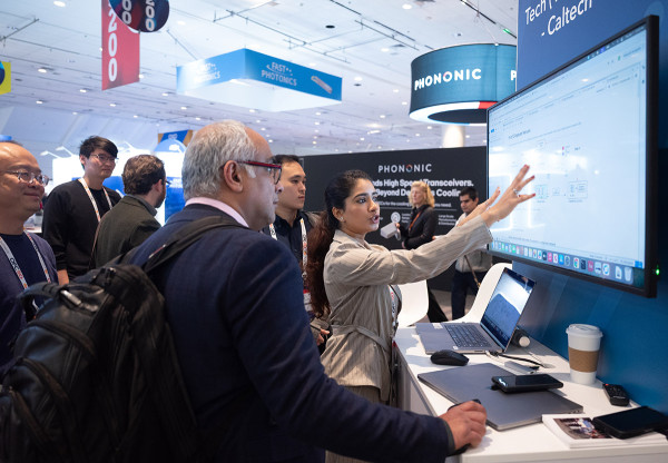 Woman gestures at a screen while people look ojn