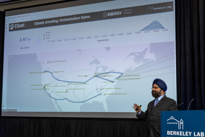 man speaking in front of projected slide reading 'ESnet6 Unveiling: Orchestration Demo'
