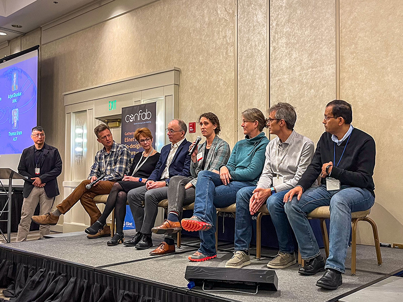 Seven people on stage, talking