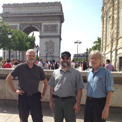 Three men in front of the Arc de Triomphe