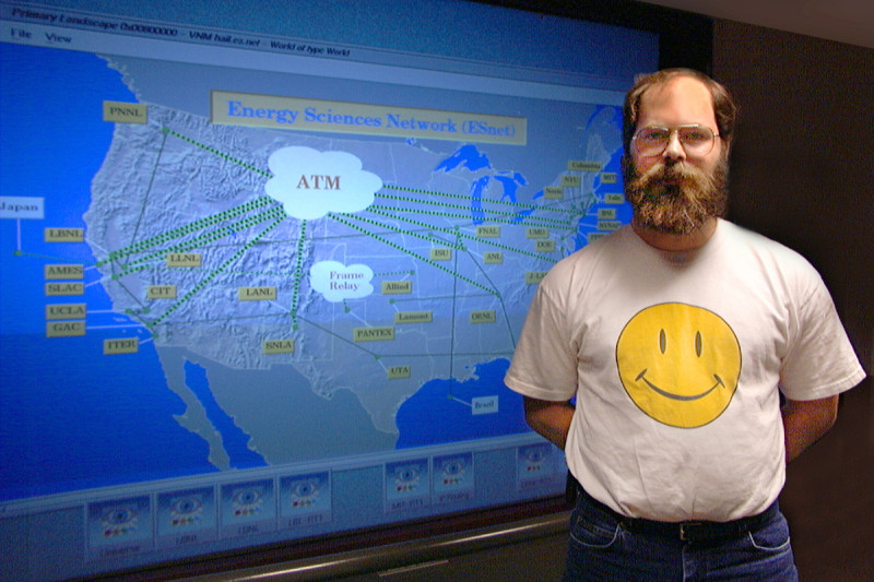 Man in happy face shirt in front of an early network map